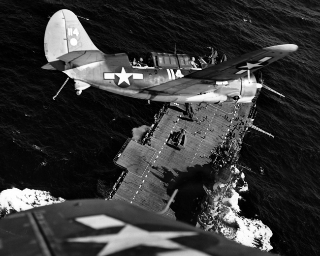 A Curtiss Helldiver circles above an aircraft carrier in the South Pacific, January 1945. U.S. Navy photo, 80-G-320999