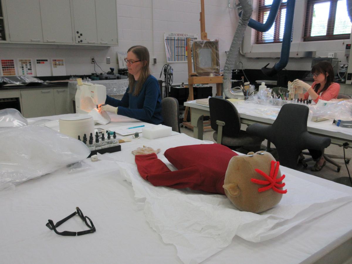 Technician sews pillow form for puppet