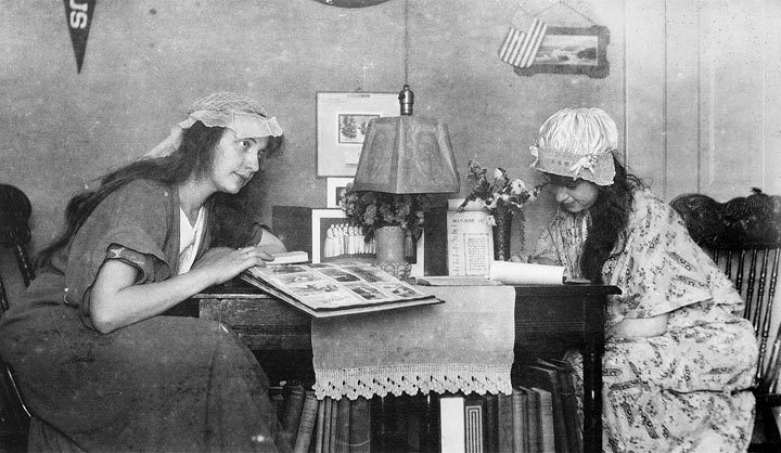 Unidentified girl looking at scrapbook in Doane College Dormitory, ca. 1920.
