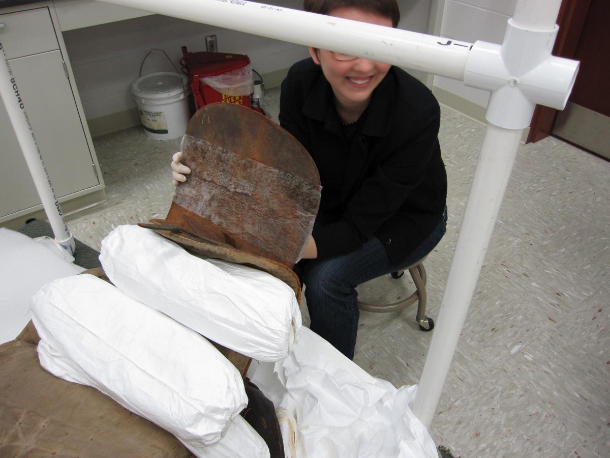 Technician holds up leather flap showing large patch of goldbeater's skin on reverse.