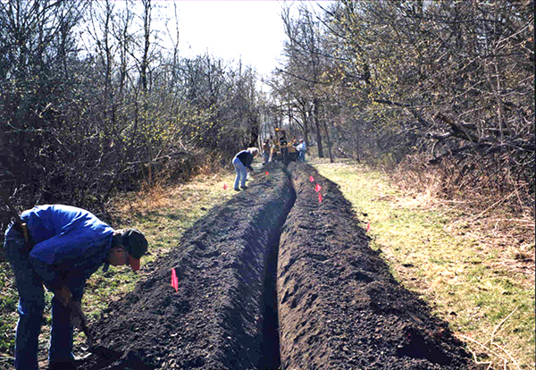 people digging in a long, narrow trench