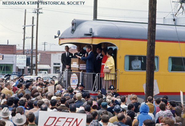 Robert F. Kennedy on railroad car platform, addressing crowd