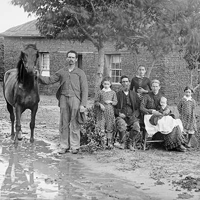 Family in muddy yard in front of sod house