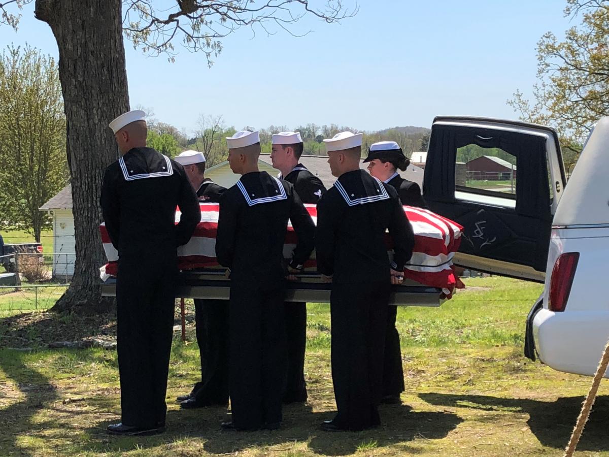 Sailors carry coffin draped in American Flag.