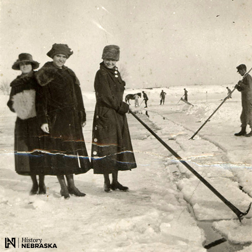 Women posing with ice harvesting poles on frozen lake