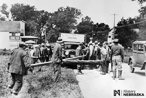 Group of men blocking highway with logs, 1930s.