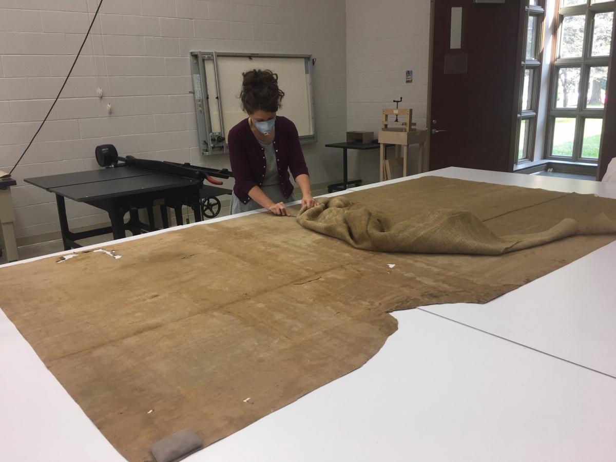 Conservator removes burlap from back of mural