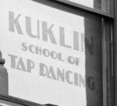 Detail of the corner drug store. A sign that reads Kuklin School of Tap Dancing