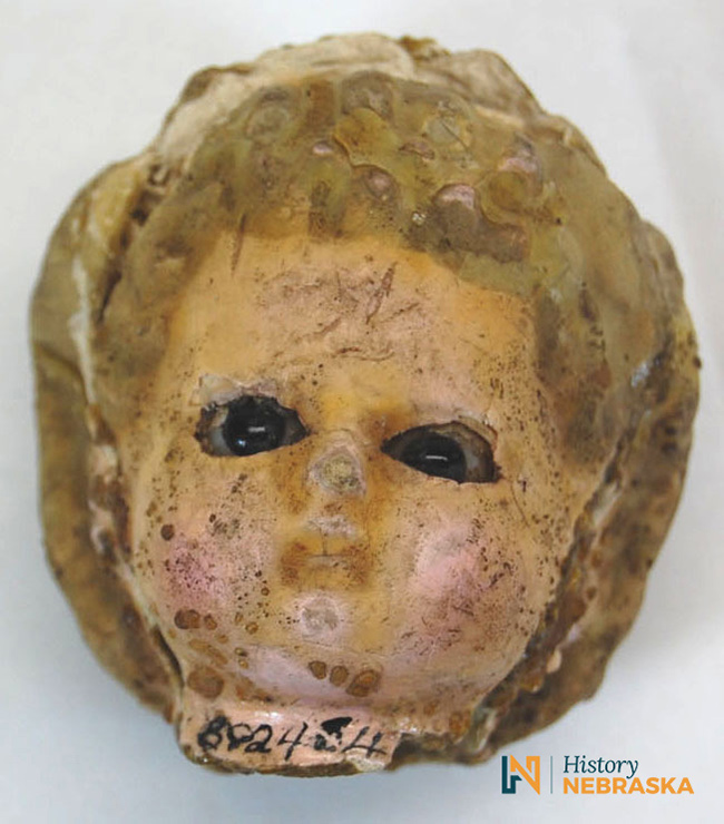 A close-up of a doll head with brown glass eyes