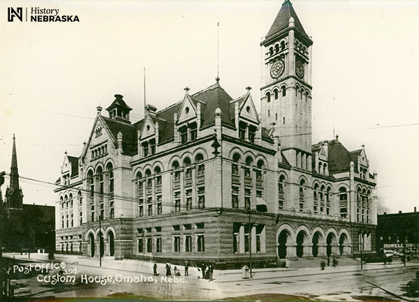 Large stone building with a clock tower. Postcard lableled "Post Office and Custom House, Omaha, Nebr."