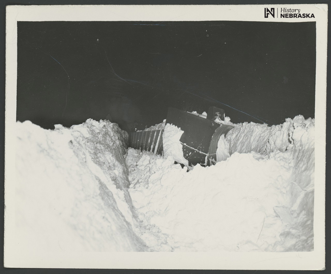 uge snowdrifts are visible on either side of a plow being used to clear railroad tracks during the Blizzard of 1949