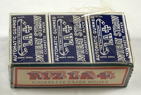 Cigarette papers (NSHS 7144-178) Cellophane wrapped carton of Riz-La+ cigarette papers containing twenty-one books of papers. The side of the carton says: "Riz La +, Cigarette Paper Books"  The top of the carton says: "Automatic Gummed, The Only Genuine LA + Wheat Straw Cigarette Paper".  The bottom of the carton says: "Thanks for the friendship trains. Back to you again since 1940, French Made Riz La+, Cigarette Paper Books, Presented by L. LACROIX Fils, ANGOULEME, Paper Makers Established 1728, Ready to resume shipments to U.S.A." 