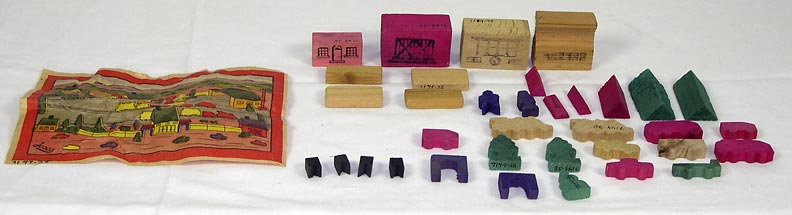 Miniature Town (NSHS 7144-38) Miniature town on a printed sheet with wooden pieces that represent buildings and vehicles. Some of the buildings have ink stamped windows and doors. 