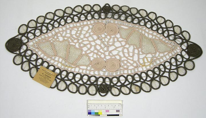 Doily (NSHS 7144-75) Doily with filet pattern and geometrical shapes. Beige and brown cord is interlaced with finer thread lacing within some leaves. Attached card says: "Spécialité de Broderies Sur Filet, Ameublement, E. NARDIN, 8 bis, Rue Pasteur, LUXEUIL-les-BAINS (Haute-Saône), R. C. LURE 5724/301, Producteur Hts-SAONE 216, C.C.P. NANCY 376l07, Téléphone 167" 