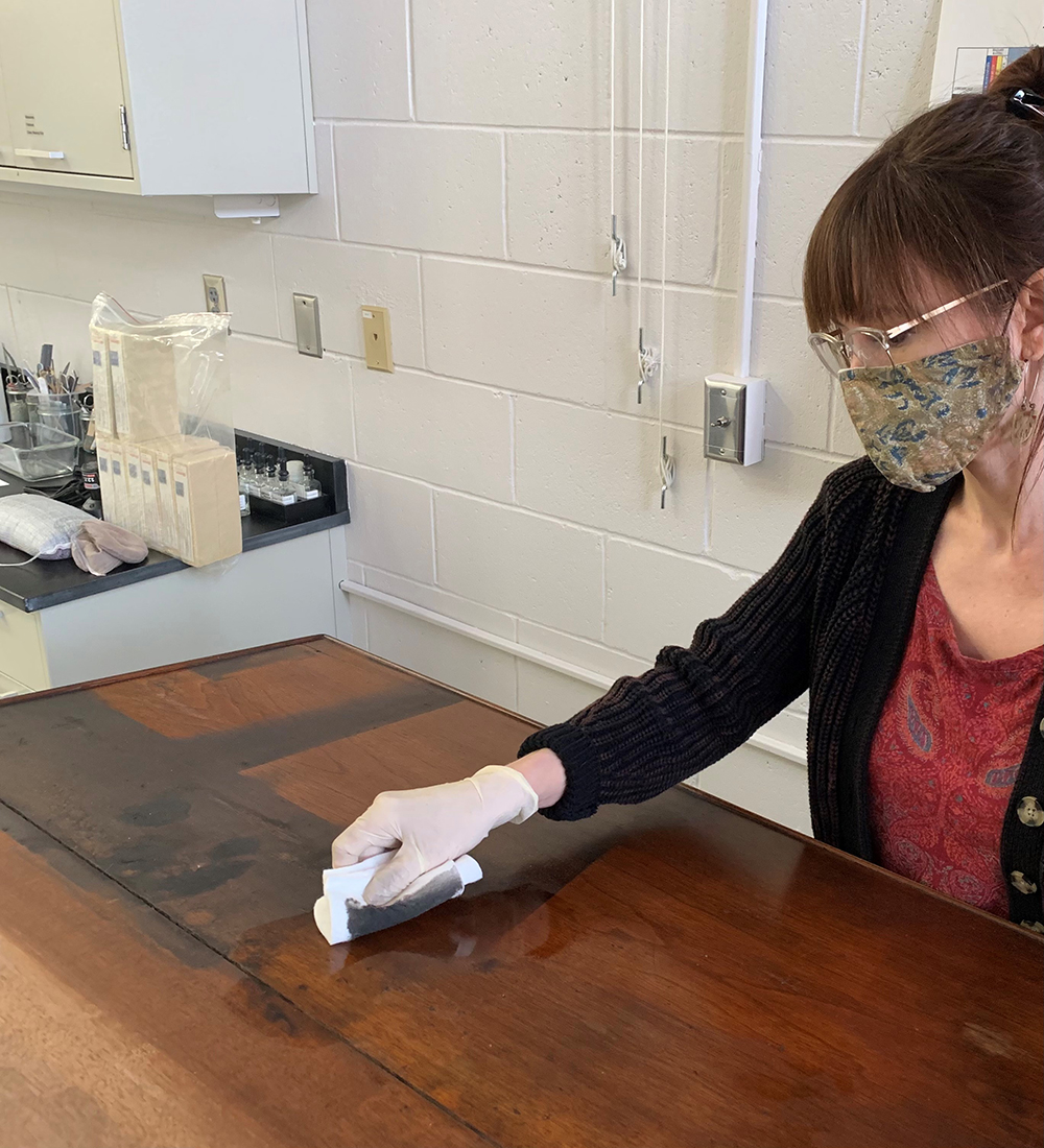 Objects Conservator Rebecca Cashman uses a cotton pad soaked in a custom aqueous cleaning solution. This solution was created in the lab after soot-removal tests were carried out.  