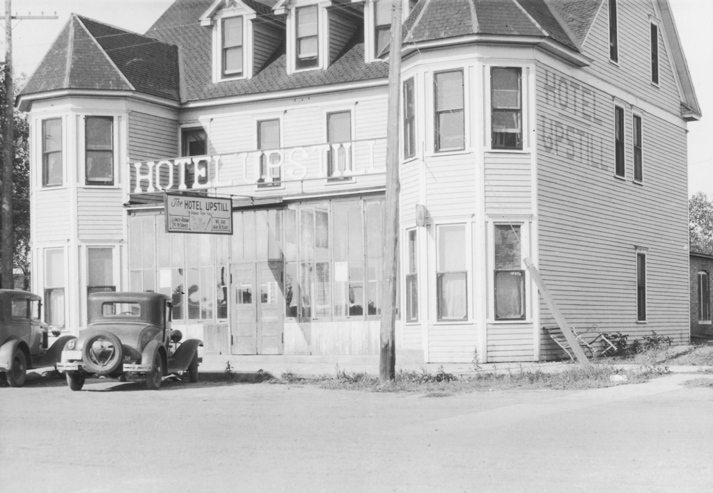 The Hotel Upstill in Long Pine, Nebraska. In front of the hotel are 1930s cars.