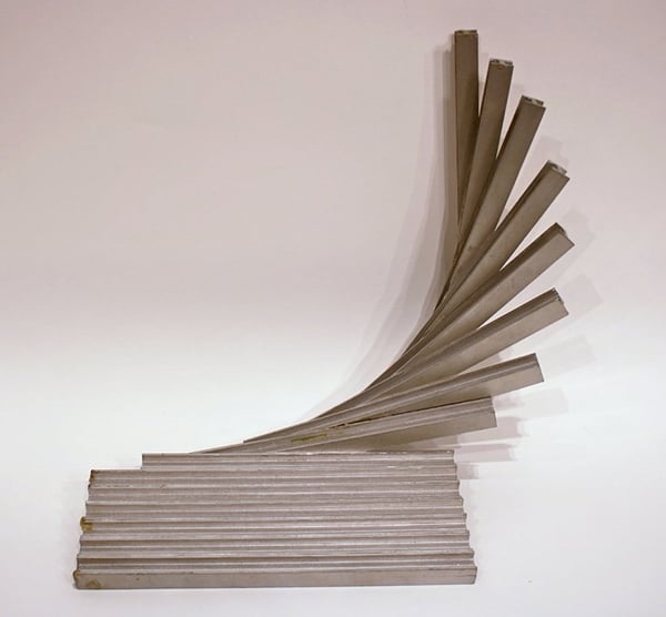 A series of metal bars are arranged in a fan-like formation, with one end fixed to the ground and the other ends raised in a curved arc.