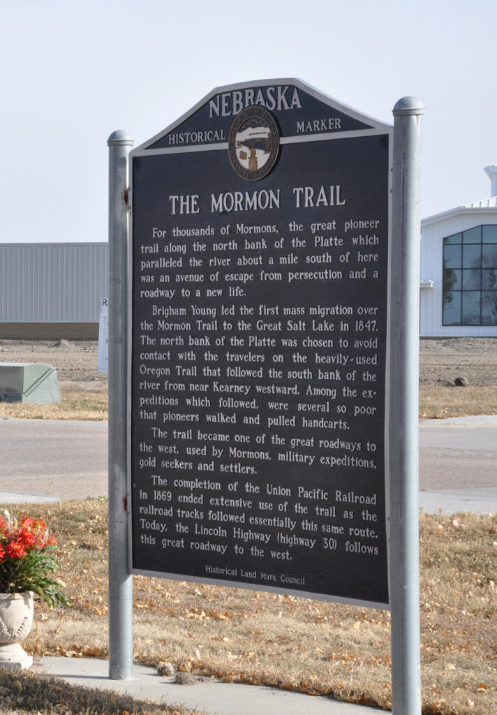Nebraska historical marker sign titled "The Mormon Trail," describing its history, significance, and use by Mormons and others, with grass and a tree in the background.