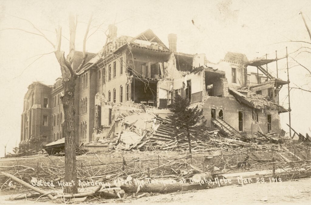 Partially destroyed multi-story brick building with debris and collapsed walls, photographed in winter; handwritten text dated January 23, 1912.