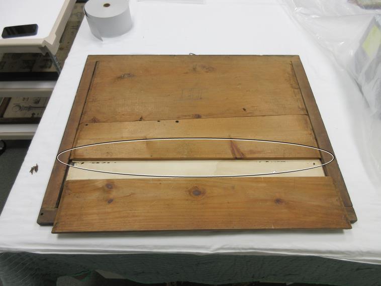 An image of the print's slatted frame, supporting where the insects entered to damage the print. Damage is visible through one slatted removed.