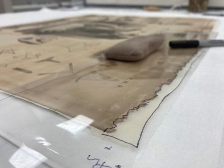 A closeup image of clear film overlaying the print. The clear film has mapped marks indicting the damaged areas of the print.