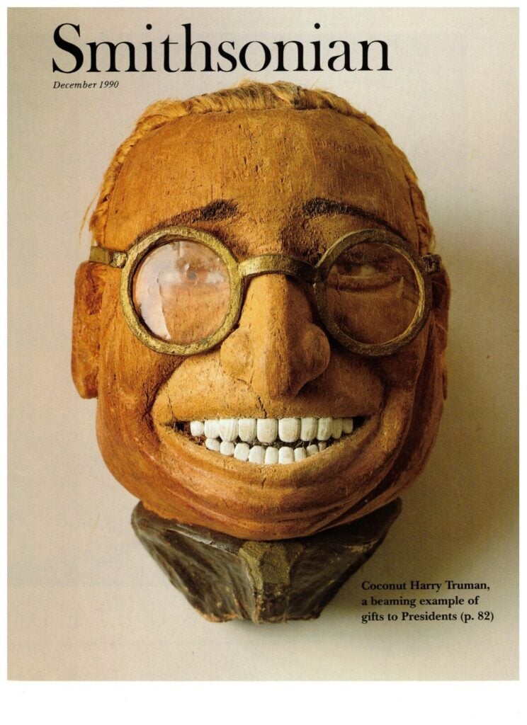 A carved coconut bust resembling Harry Truman with glasses and a wide smile, featured on the cover of Smithsonian magazine, December 1990.