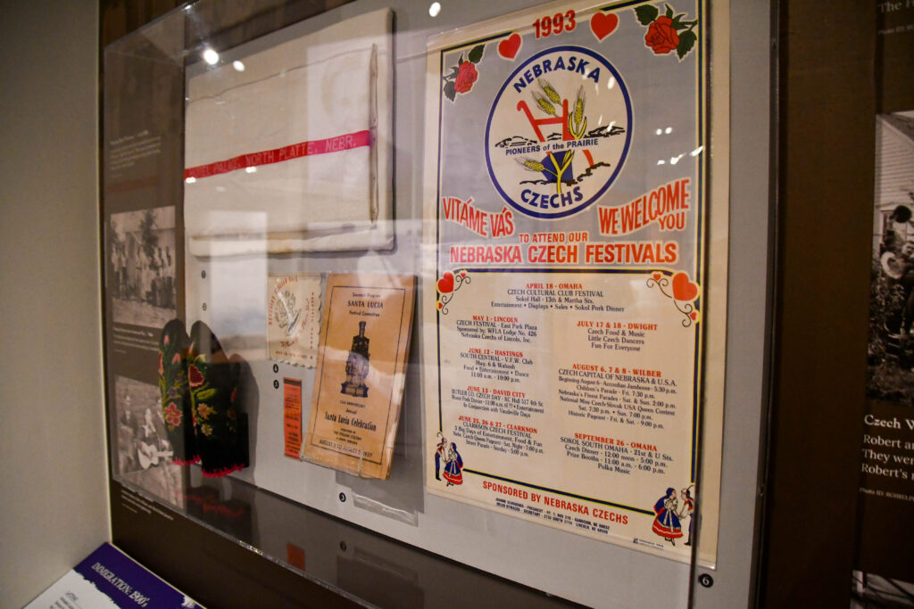 Display case with a flyer for the 1993 Nebraska Czech Festival, pamphlets, a traditional apron, photographs, and other related items.